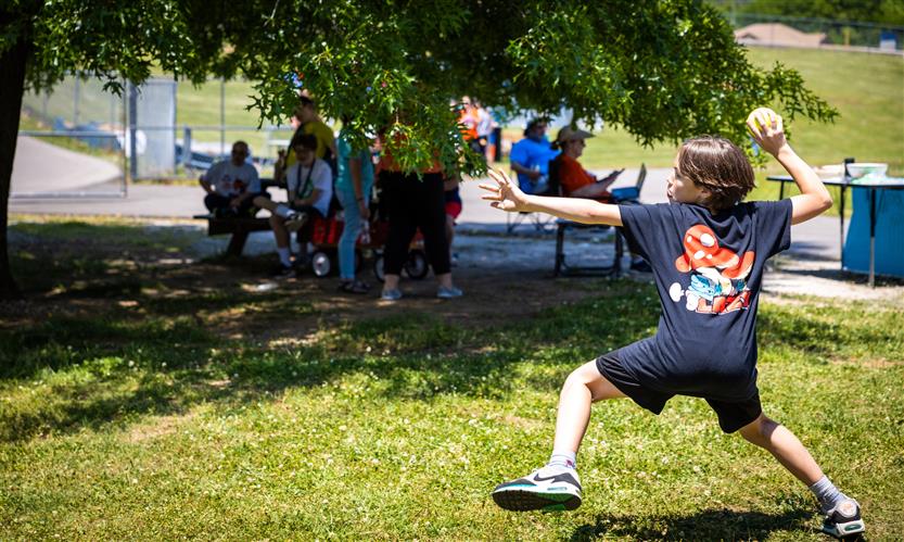A student in the middle of throwing a softball